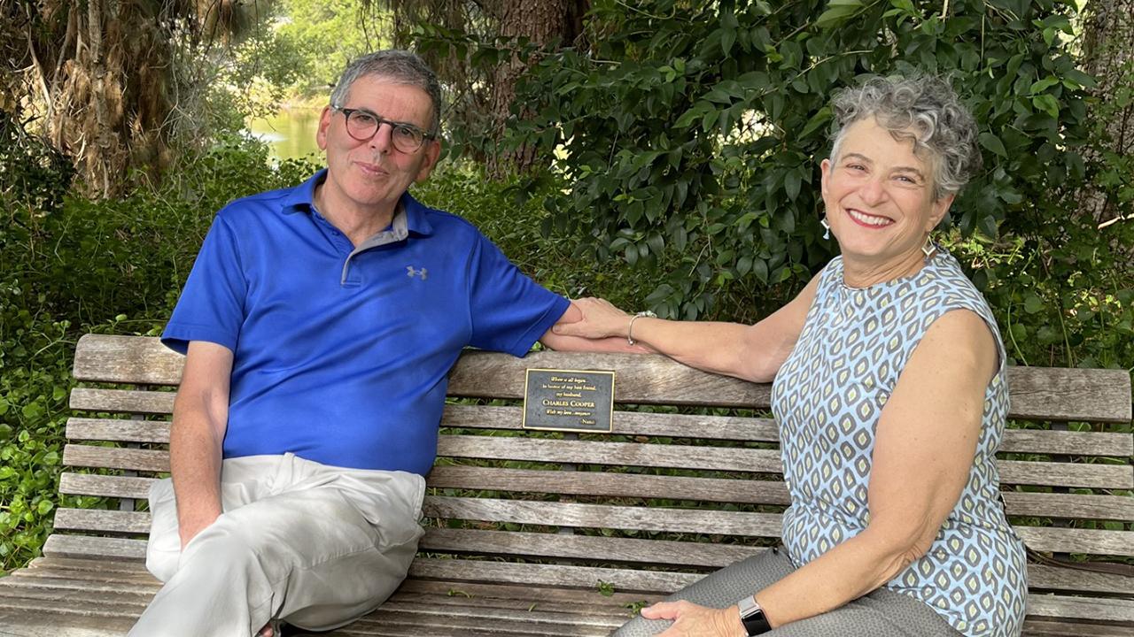 Alumni couple Charles and Nancy Cooper sit together on a bench in the UC Davis Arboretum and Public Garden. 