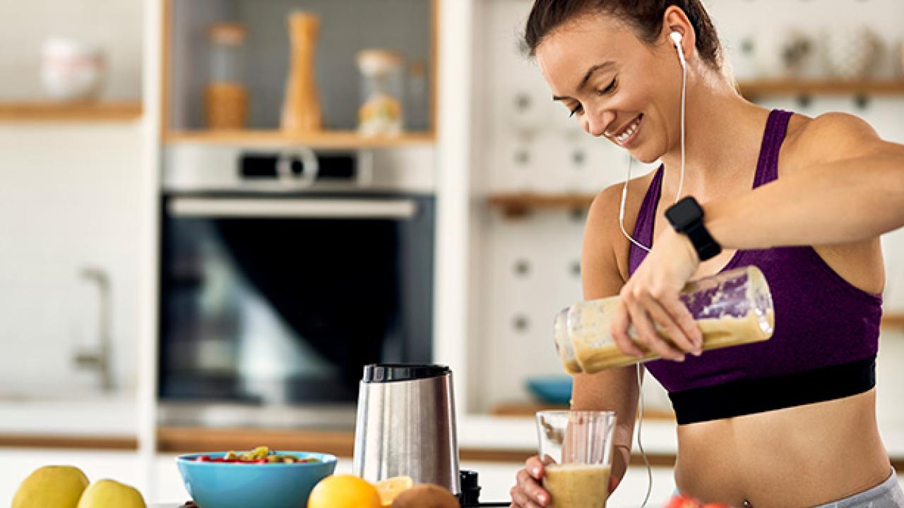 Athletic woman in the kitchen making a smoothie