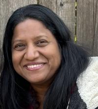 Dark-haired person standing outside in a red vest