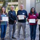 Five award recipients stand outdoors with the dean holding certificates during the CBS 20th anniversary celebration at UC Davis