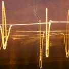 Golden light trails form jagged, wave-like lines against a dark background, resembling an abstract heart monitor.